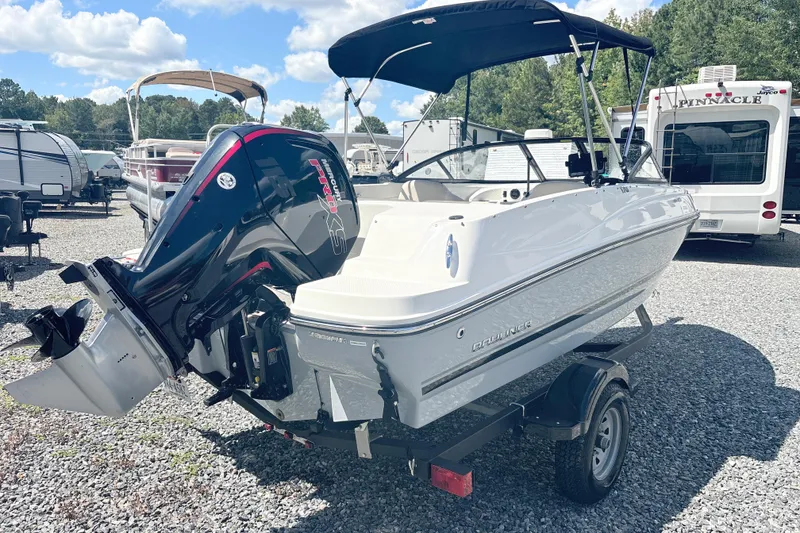 Slide: The Image of 2020 Bayliner 170 Bowrider boat with outboard motor on a trailer, parked outdoors. - 6