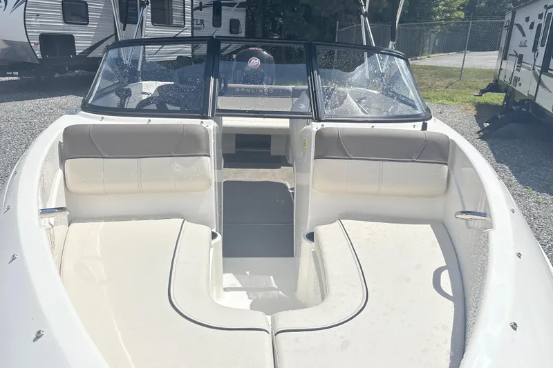 Slide: The Image of 2020 Bayliner 170 Bowrider boat interior with seating and windshield, parked outdoors. - 8