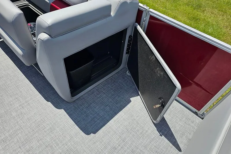 Slide: The Image of 2026 Sun Tracker Party Barge 20 DLX storage compartment with open door, gray seating, and red panel. - 14