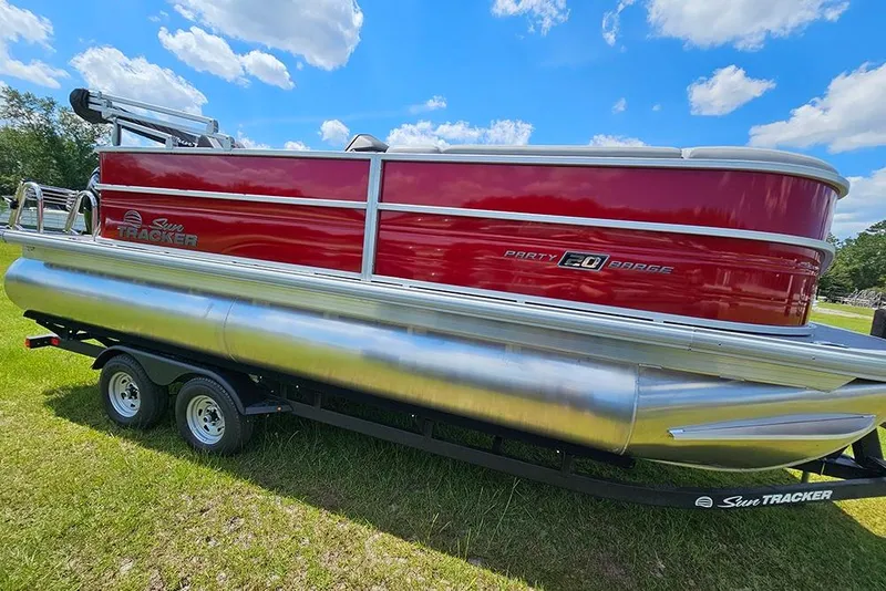 Slide: The Image of 2026 Sun Tracker Party Barge 20 DLX pontoon boat on trailer, grassy field background. - 6