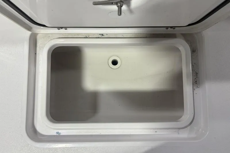 Slide: The Image of 2025 Sportsman Masters 267OE Bay Boat storage compartment, open lid, white interior. - 24