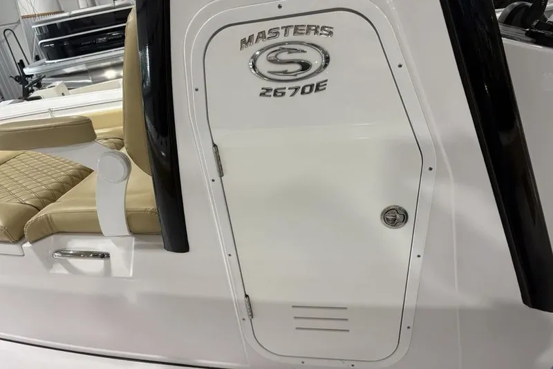 Slide: The Image of 2025 Sportsman Masters 267OE Bay Boat interior with beige seating and storage compartment. - 9