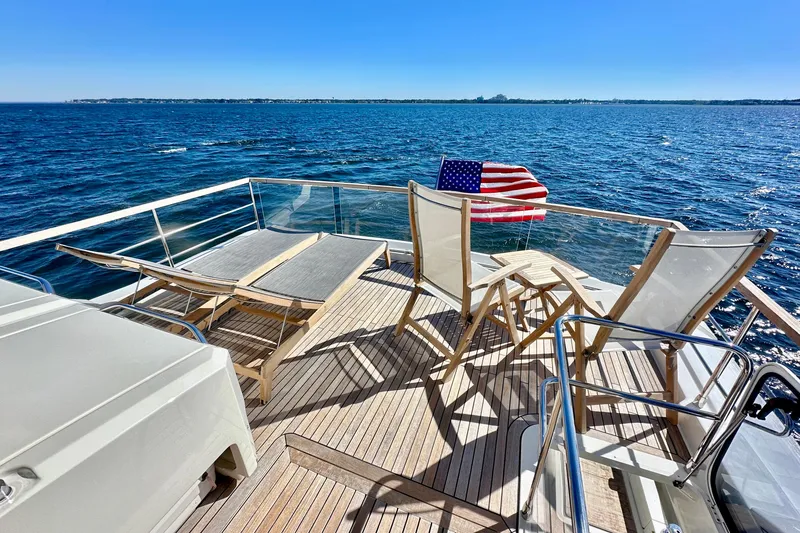 Slide: The Image of Luxury Absolute 72 FLY yacht deck with chairs, American flag, and ocean view, 2016 model. - 60