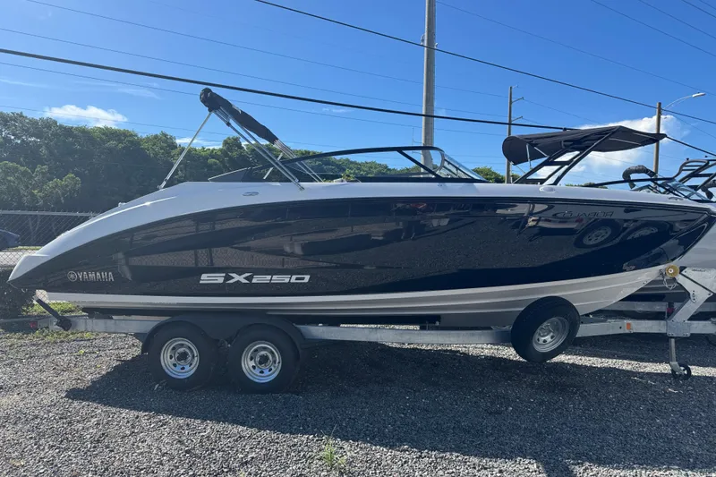 The Image of 2025 Yamaha Boats SX250 on trailer, sleek design, parked outdoors under clear blue sky. - 1