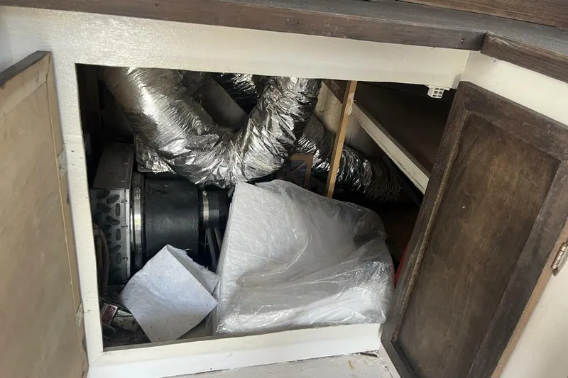 Slide: The Image of Open cabinet on 1983 Custom Key West 39' Sportfish, showing ductwork and storage items. - 13