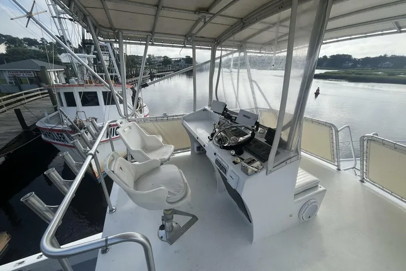 Slide: The Image of 1983 Custom Key West 39' Sportfish boat helm with dual seats, docked by calm waters. - 26