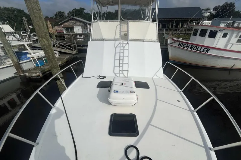 Slide: The Image of 1983 Custom Key West 39' Sportfish boat docked, featuring spacious deck and ladder. - 36