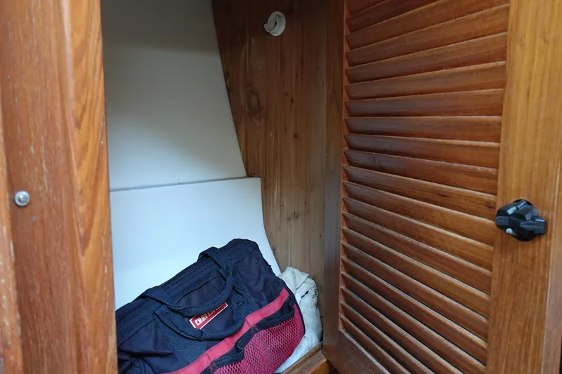 Slide: The Image of Wooden cabinet interior with a black and red bag inside a 1997 Catalina 28 sailboat. - 32