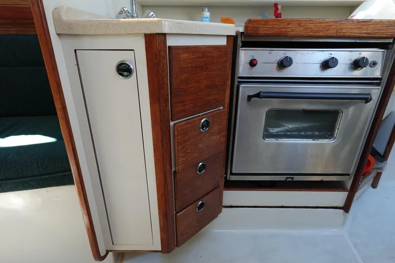 Slide: The Image of 1997 Catalina 28 yacht kitchen with stove, wooden cabinets, and sink. - 42