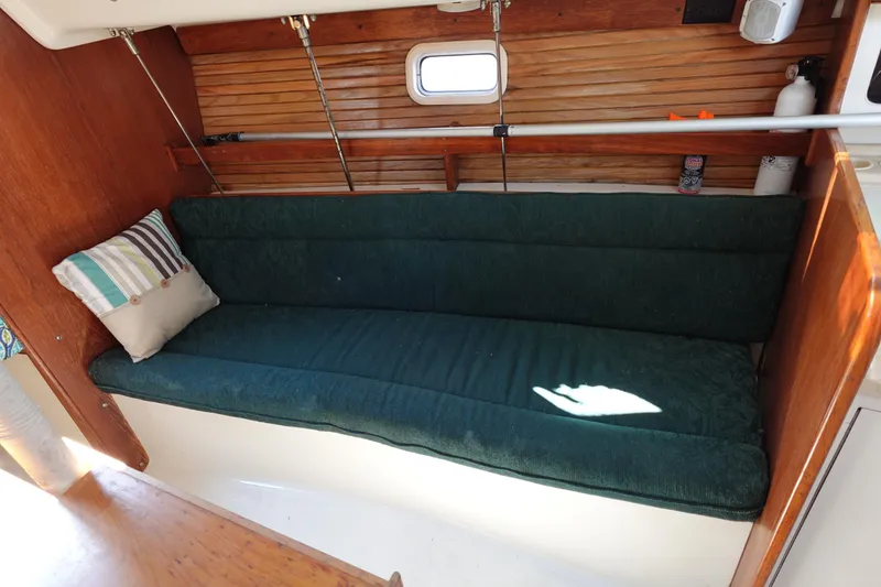 Slide: The Image of Interior of a 1997 Catalina 28 sailboat with green cushioned seating and wooden paneling. - 49
