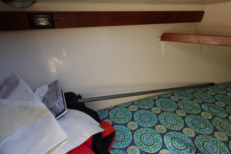 Slide: The Image of Interior of a 1997 Catalina 28 sailboat with patterned bedding and storage shelves. - 57
