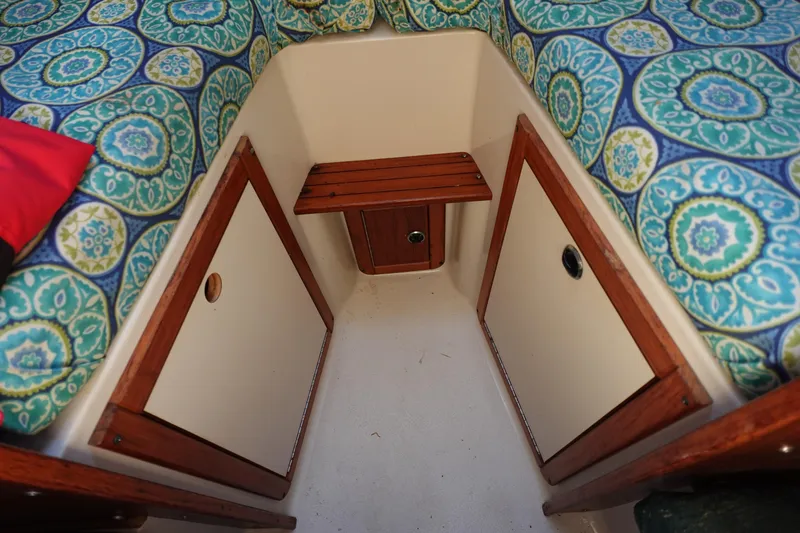 Slide: The Image of Interior of a 1997 Catalina 28 sailboat with patterned cushions and wooden storage. - 59