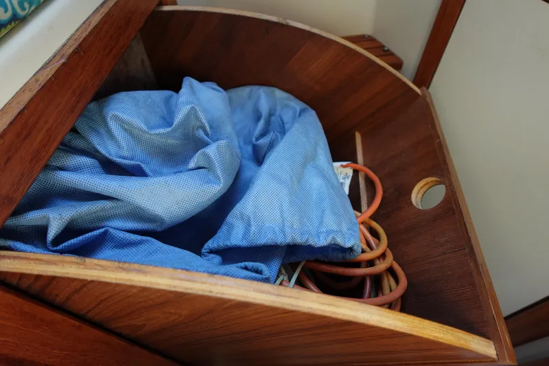 Slide: The Image of Wooden storage compartment in a 1997 Catalina 28 sailboat with blue fabric and cables. - 64