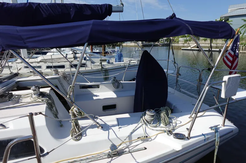 Slide: The Image of 1997 Catalina 28 sailboat docked, featuring blue canopy and American flag. - 8