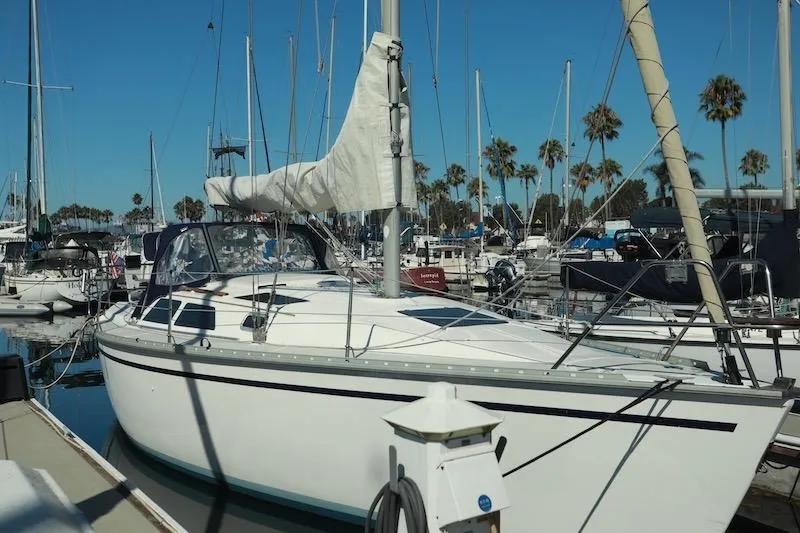 The Image of 1989 Hunter 30 sailboat docked in a marina with palm trees in the background. - 0