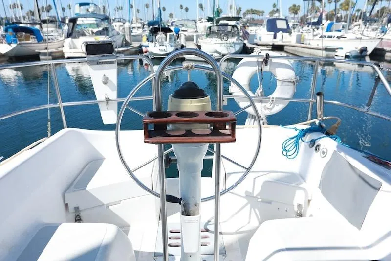 Slide: The Image of Cockpit of a 1989 Hunter 30 sailboat in a marina, featuring a steering wheel and cup holders. - 2