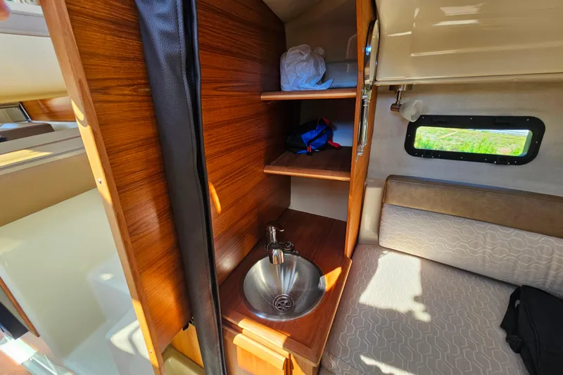 Slide: The Image of 2021 Ranger Tugs R-23 interior with wooden cabinetry, sink, and seating area. - 13