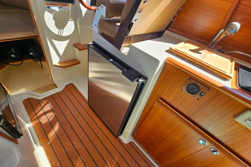 Slide: The Image of 2021 Ranger Tugs R-23 interior with wood finish, compact kitchen, and mini fridge. - 14