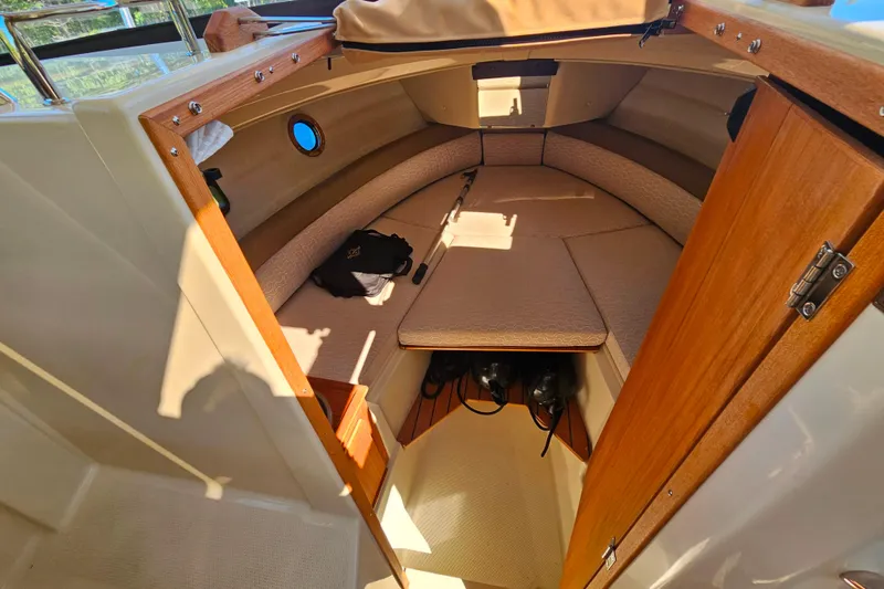 Slide: The Image of 2021 Ranger Tugs R-23 cabin interior with cozy seating and wooden accents. - 16