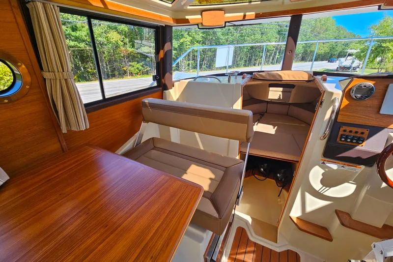 Slide: The Image of 2021 Ranger Tugs R-23 interior with wood accents and seating, showcasing helm and cabin area. - 18