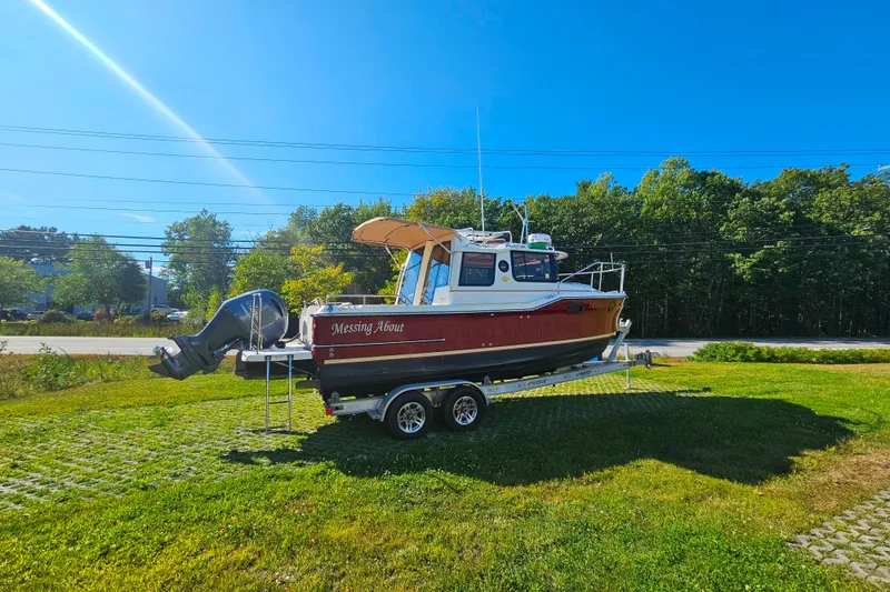 Slide: The Image of 2021 Ranger Tugs R-23 boat on trailer, parked on grassy area under clear blue sky. - 2