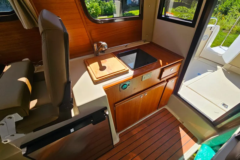 Slide: The Image of 2021 Ranger Tugs R-23 interior with wooden cabinetry, sink, and seating. - 20