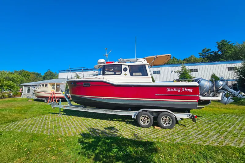 Slide: The Image of 2021 Ranger Tugs R-23 boat on trailer, vibrant red hull, parked outdoors. - 3