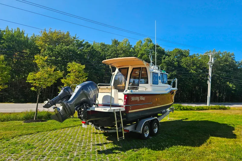Slide: The Image of 2021 Ranger Tugs R-23 boat on trailer, parked on grass, with trees in background. - 5