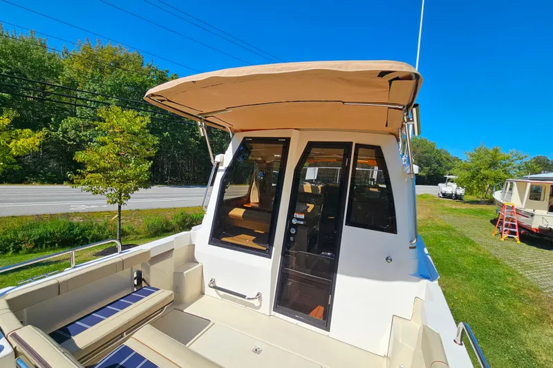 Slide: The Image of 2021 Ranger Tugs R-23 boat with canopy, docked on grassy area under clear blue sky. - 6