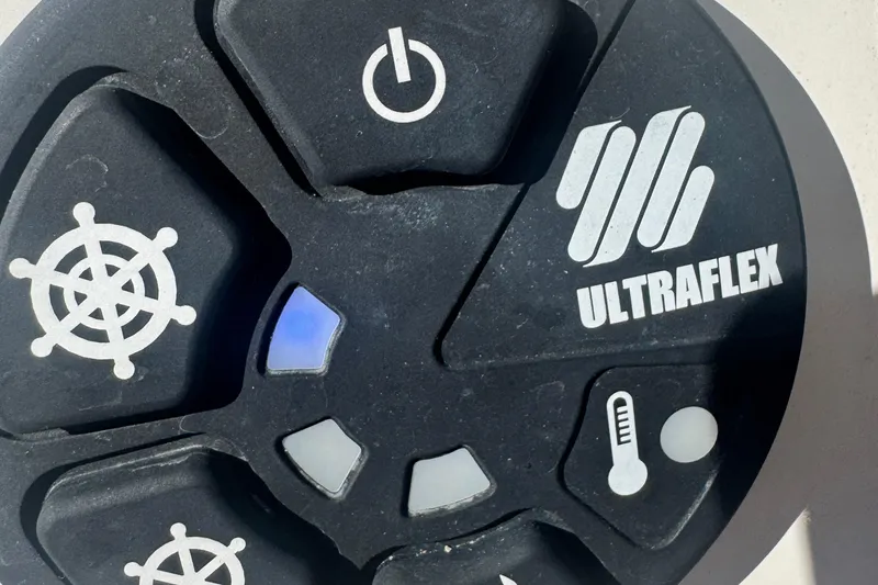 Slide: The Image of Ultraflex control panel on 2024 Sailfish 241 CC boat, featuring steering and temperature icons. - 17