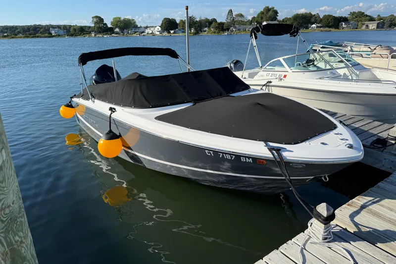 Slide: The Image of 2021 Regal LX2 boat docked with black cover and orange fenders on a sunny day. - 2