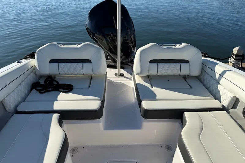 Slide: The Image of 2021 Regal LX2 boat interior with cushioned seating and outboard motor on calm water. - 4