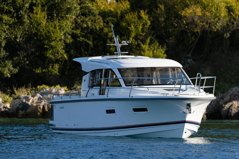 The Image of Nimbus 305 Coupe 2026 cruising on a serene waterway, surrounded by lush greenery. - 0