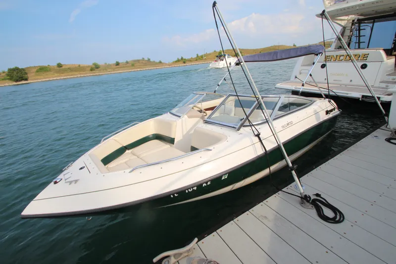 The Image of 1999 Bryant 182 boat docked on calm water, clear sky in background. - 1