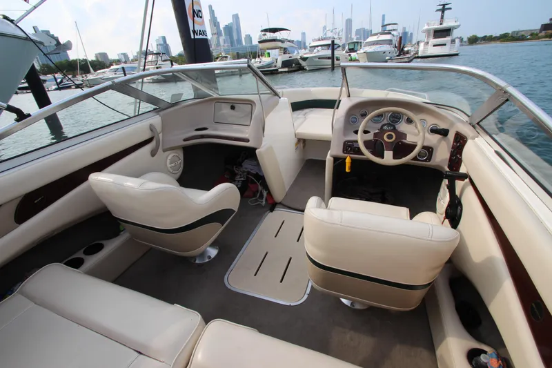 Slide: The Image of Interior of a 1999 Bryant 182 boat with beige seating and city skyline in background. - 15