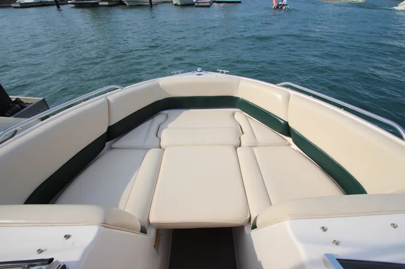 Slide: The Image of 1999 Bryant 182 boat interior with beige and green seating on water. - 23