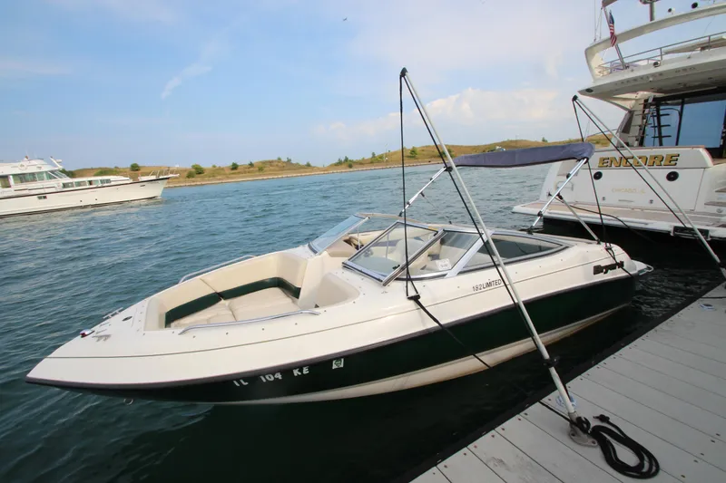 Slide: The Image of 1999 Bryant 182 boat docked on a calm lake with clear skies. - 24
