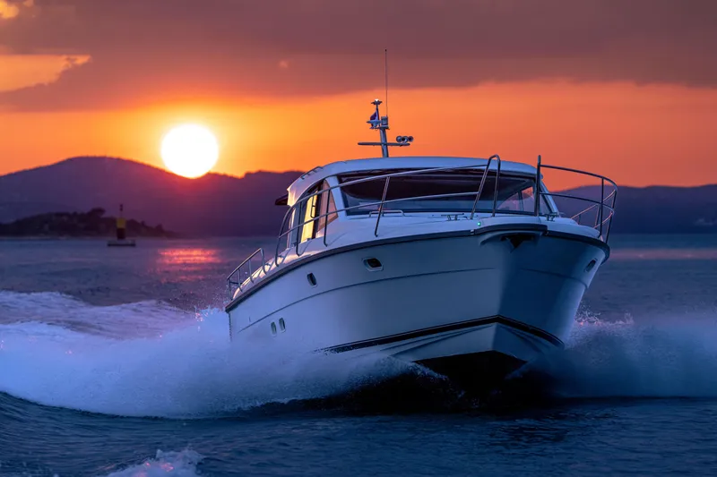 Slide: The Image of Nimbus 405 Coupé 2026 cruising at sunset, creating waves on the water. - 3