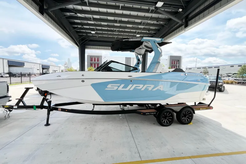 Slide: The Image of 2025 Supra SA450 boat on trailer under a canopy, showcasing sleek design. - 1