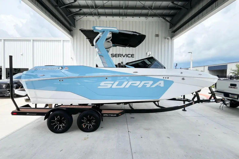 Slide: The Image of 2025 Supra SA450 boat on trailer, blue and white design, parked at service center. - 4
