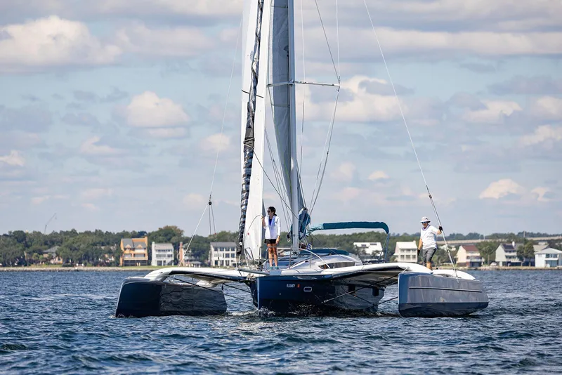 Slide: The Image of Sailing the 2025 Dragonfly 32 Evolution trimaran on a sunny day near coastal homes. - 17