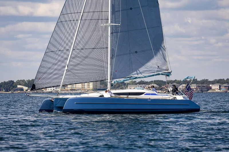 Slide: The Image of Sailing on water, Dragonfly 32 Evolution 2025 trimaran with blue hull and large sails. - 2