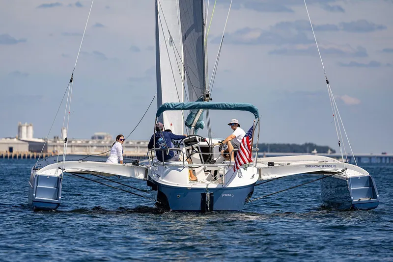 Slide: The Image of Sailing on a Dragonfly 32 Evolution trimaran, 2025 model, with American flag on open water. - 27