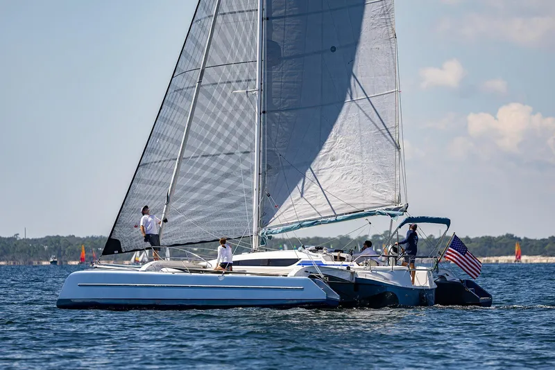 Slide: The Image of Sailing on a Dragonfly 32 Evolution trimaran, 2025 model, with American flag on open water. - 34