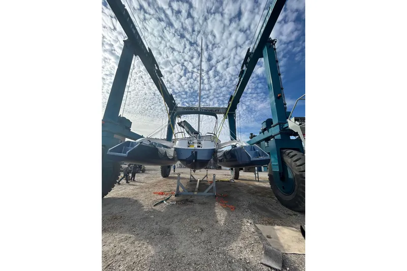 Slide: The Image of 2025 Dragonfly 32 Evolution sailboat on a lift under a cloudy sky. - 48