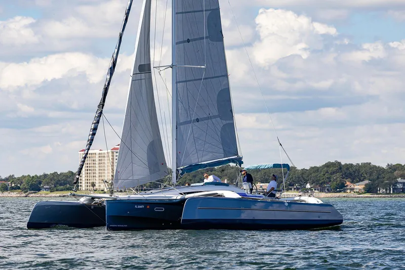 Slide: The Image of 2025 Dragonfly 32 Evolution sailboat cruising on a sunny day with scenic shoreline backdrop. - 6