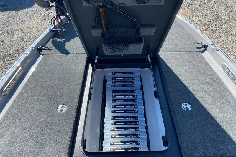 Slide: The Image of 2026 Skeeter FXR21 FLEX boat storage compartment with organized tackle boxes. - 14