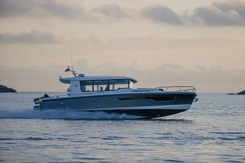 Slide: The Image of 2026 Nimbus Commuter 11 boat cruising on calm waters at sunset. - 2