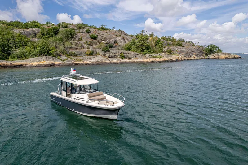 Slide: The Image of 2025 Nimbus Commuter 8 boat cruising near rocky shoreline under blue sky. - 3