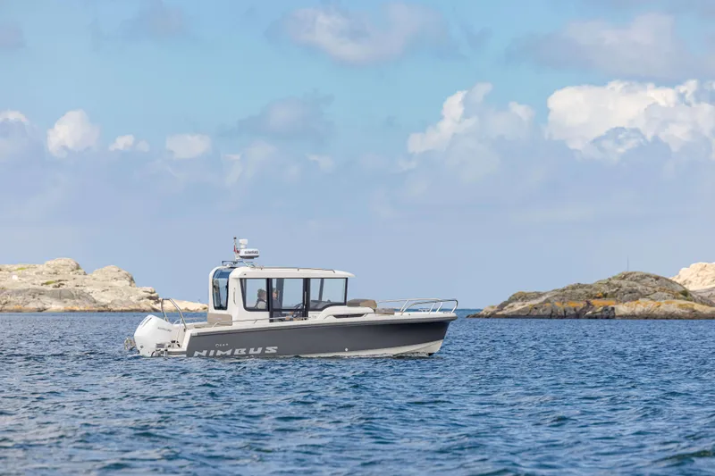 Slide: The Image of 2025 Nimbus Commuter 8 boat cruising on a calm sea with rocky islands in the background. - 8